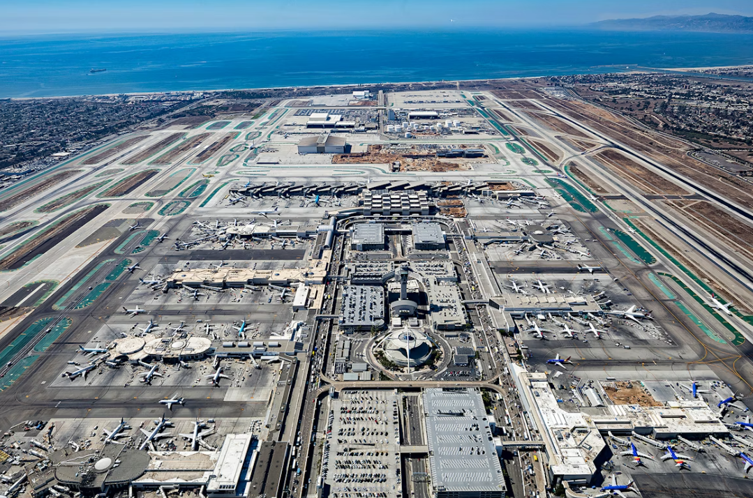 Aerial view of a large airport with a blue sky and ocean in background