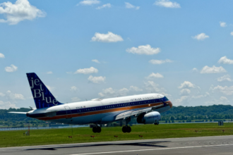 A large blue and white jetliner flying through a blue sky