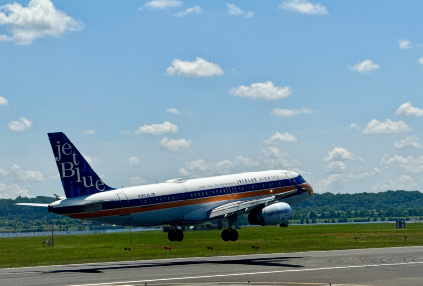A large blue and white jetliner flying through a blue sky
