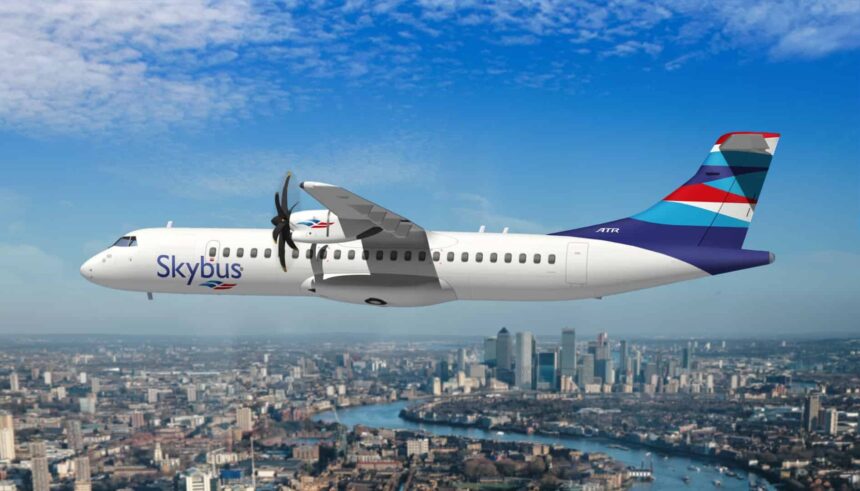 Skybus aircraft flying over a city, lake in the background, blue sky.