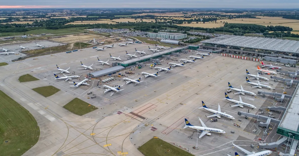 London Stansted Airport from a bird's eye view with lots of planes on the ground next to the airport's buildings. 