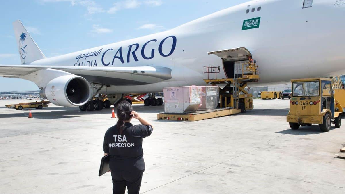 A picture of an TSA agent in front of an cargo aircraft