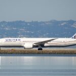 United Airlines Boeing 878-9 Dreamliner on the runway. Lake in front of the aircraft beside the runway.