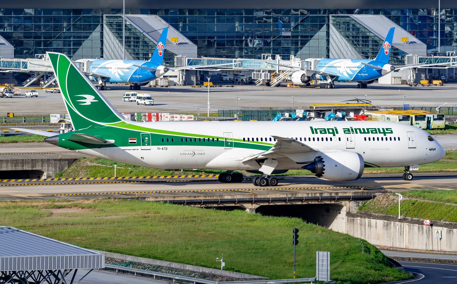 Iraqi Airways B787 Dreamliner taxing in a over-taxiway with the background of two other B787 aircraft of China Southern Airlines parked at the apron area at Guangzhou Baiyun Airport. 