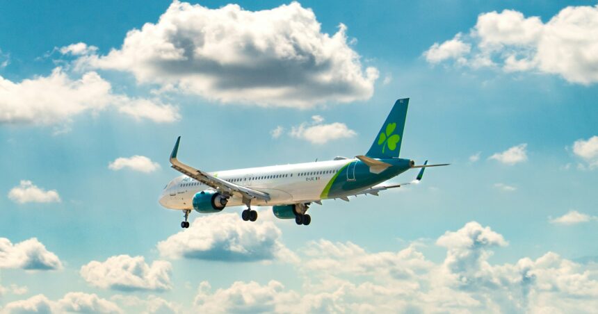 Aer lingus aircraft in a clear light blue sky with some clouds.