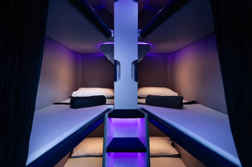 Air New Zealand's new Skynest sleeping pods, with purple ambient lighting and two beds facing the camera.