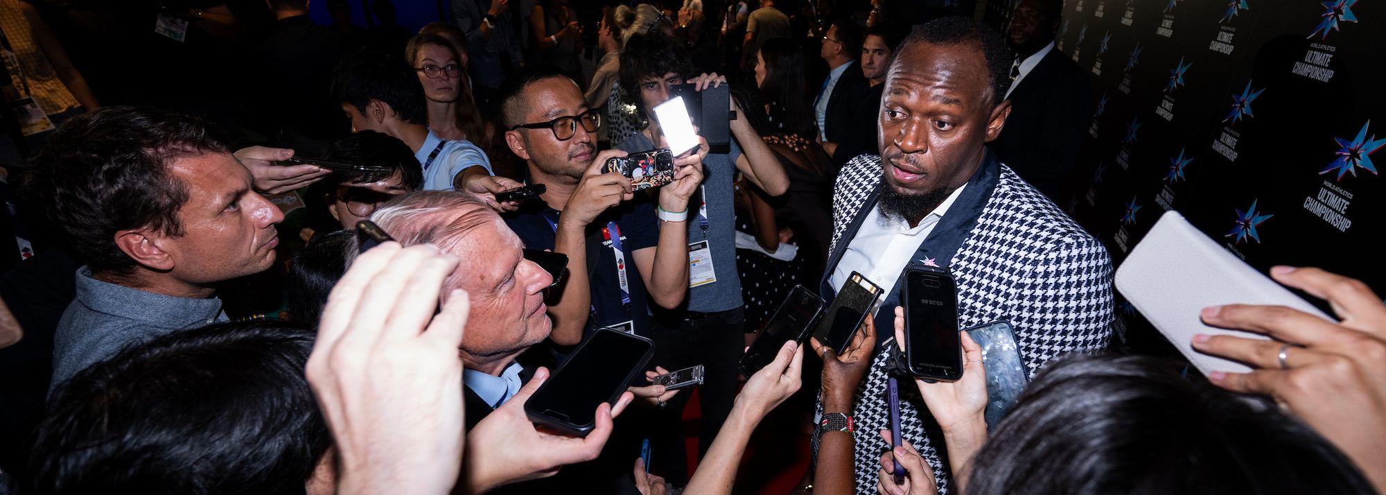 Usain Bolt at the World Athletics Ultimate Championship one-year countdown party. Crowd of people interviewing him.