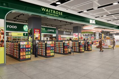 The image shows a dual branded Waitrose-Relay shop inside London Heathrow Airport Terminal 2. Along the top of the image is the dual branded logo in forest green and white. A range of colourful displays can be seen on stalls and shelves in the shop.