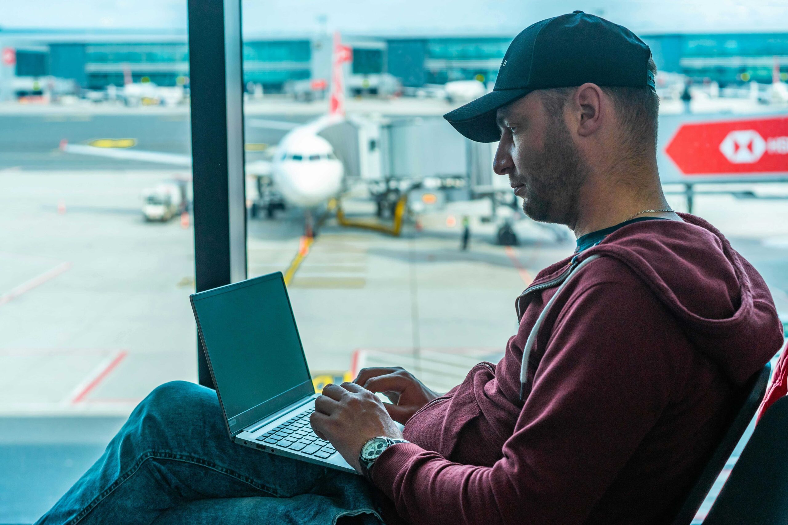 Man in Hoodie Jacket Sitting on a Chair Using Laptop at the airport
