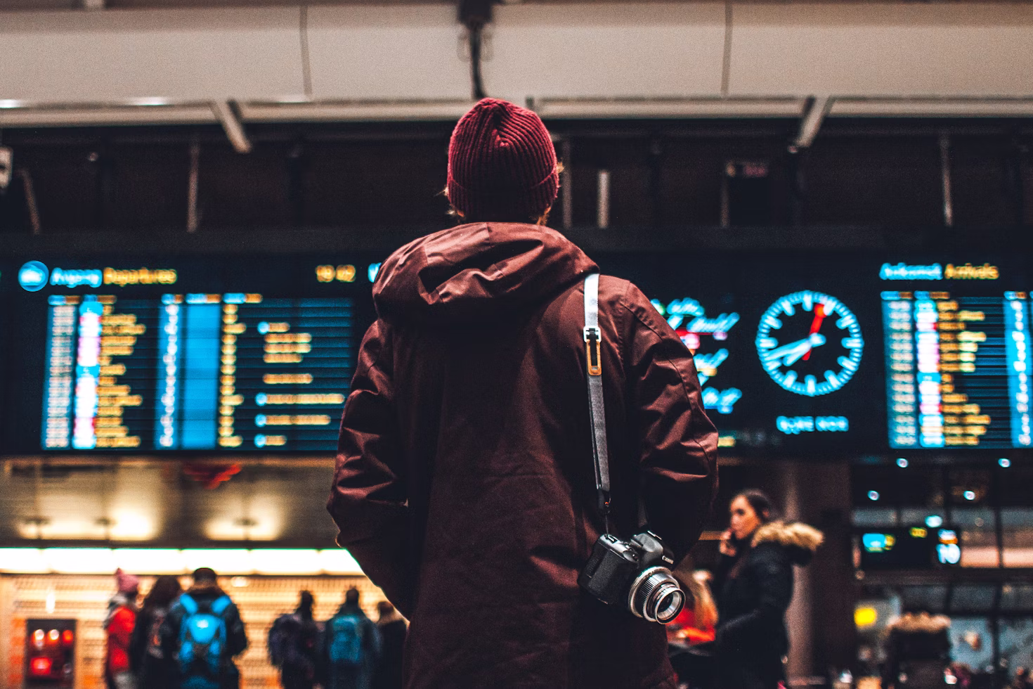 Man standing in front of screen showing flight departures and arrivals