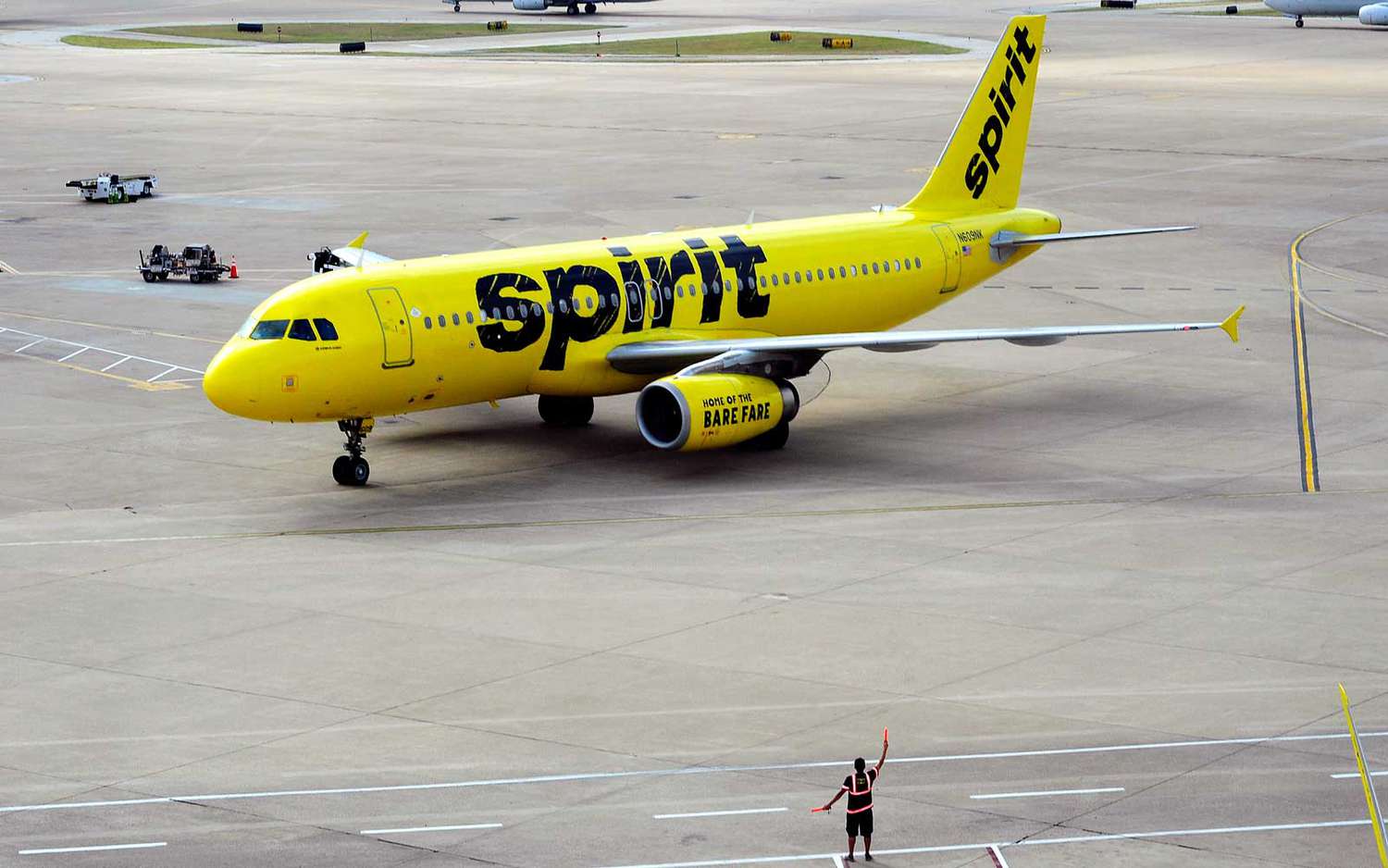 Airport worker directing a Spirit aircraft to runway