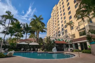 Exterior of Renaissance Hotel in Fort Lauderdale, pool and palm trees in view, blue sky.
