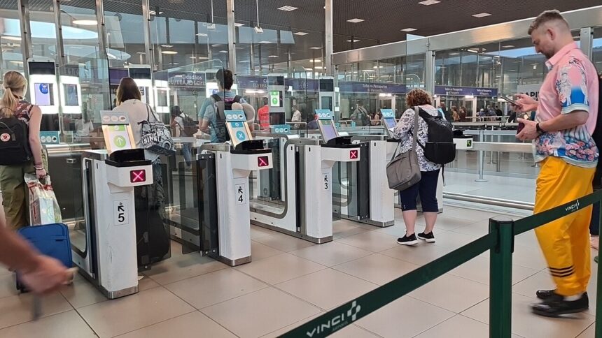 Travellers pass through automated e-gates at Lisbon Airport while border checks are carried out inside the terminal.