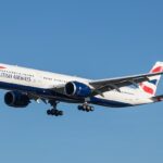 A British Airways A350 flying under a blue sky. Its livery is a mix of white, blue and red.