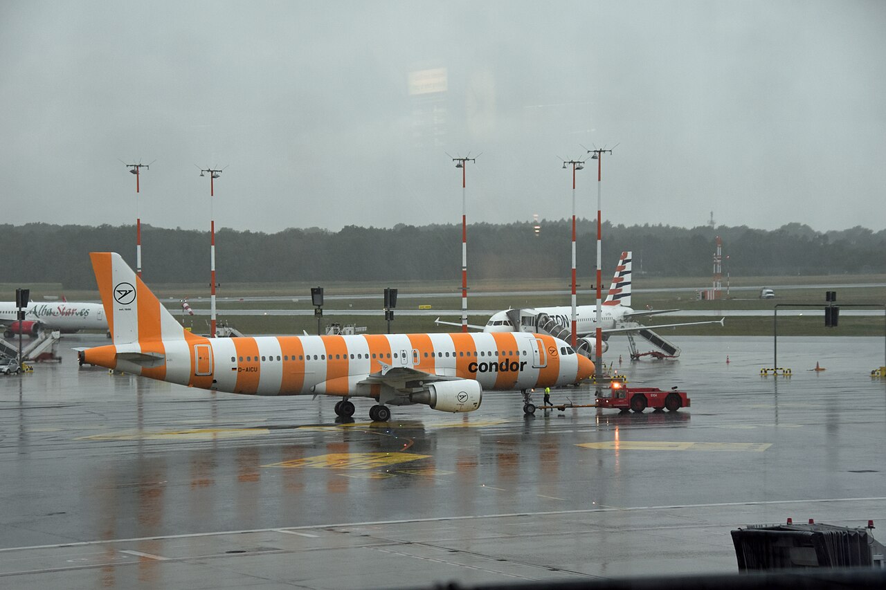 Stripped white and orange Condor airbus on the tarmac at Hamburg international airport on a wet grey day.