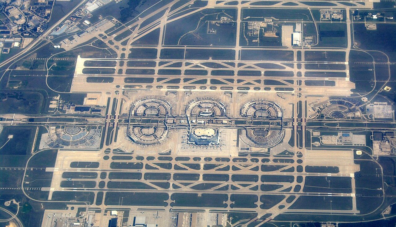Aerial view of Dallas Fort Worth International Airport. Several planes are seen parked at the gates.