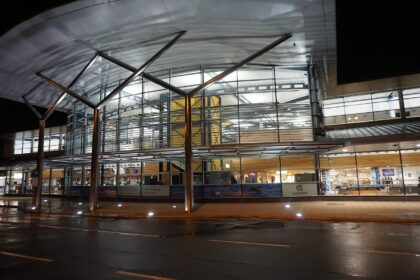 Arrivals area of GCI airport captured at night. Lights on in the building.