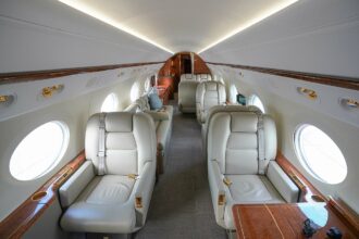 Luxury interior of a Gulfstream G450 private jet featuring cream leather seats, wood trim and spacious seating arrangements.