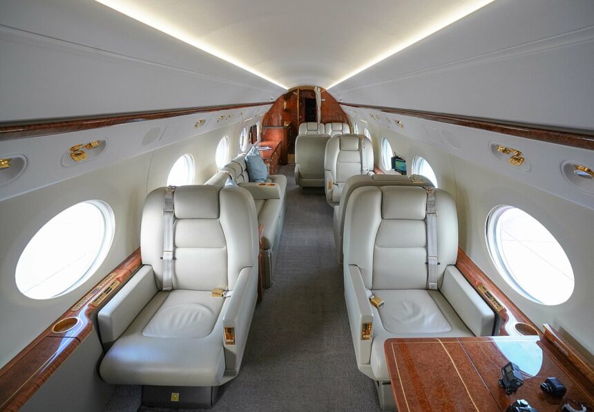 Luxury interior of a Gulfstream G450 private jet featuring cream leather seats, wood trim and spacious seating arrangements.