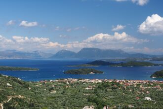 View of small green islands in the Ionian Sea near Lefkada, Greece, with calm blue water, rocky shoreline.