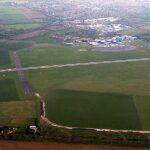 View of a runway and surrounding airfield buildings at London Oxford Airport under a clear sky.