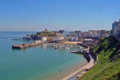 Colourful houses overlook Tenby Harbour in Pembrokeshire, Wales, with fishing boats resting in the harbour at low tide.