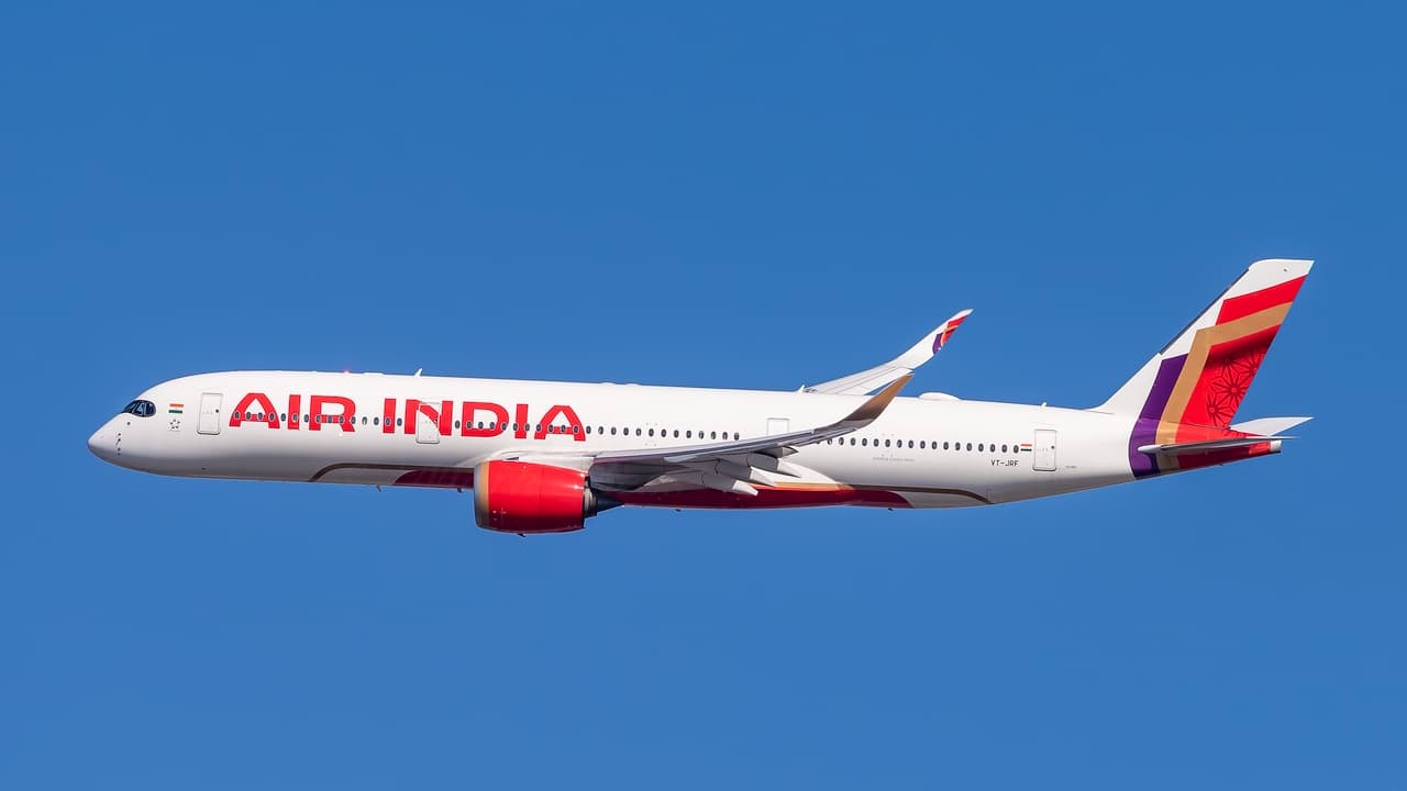 Air India A350 flying under a blue sky. The airline's logo is written in red, with a white fuselage. 