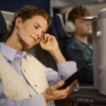 Lady sat in a first class Allegris seat on her phone looking content and comfortable.