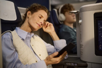 Lady sat in a first class Allegris seat on her phone looking content and comfortable.