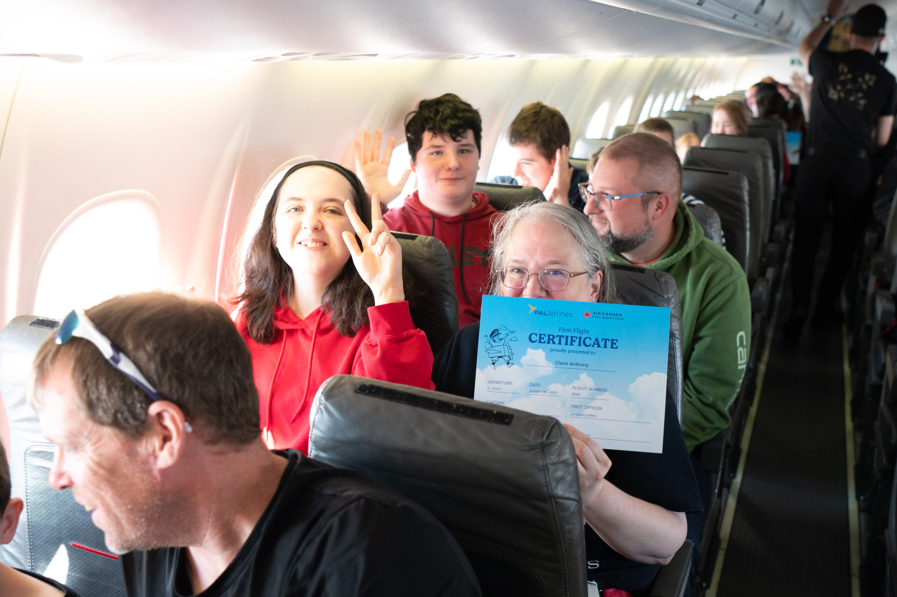 Young people and adults on board an aircraft with a lady holding a certificate for completing the Autism Aviation Day programme.