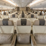 Three cream, leather seats on an aircraft are at the forefront of the image with more seats shown in the background
