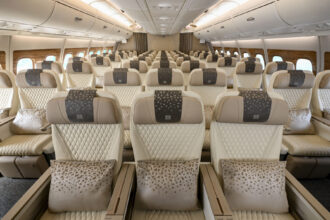 Three cream, leather seats on an aircraft are at the forefront of the image with more seats shown in the background
