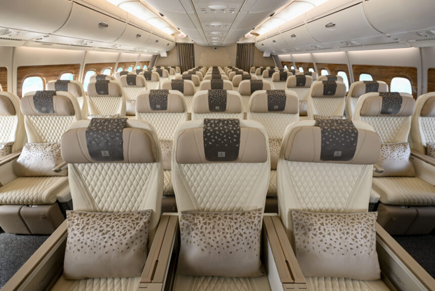 Three cream, leather seats on an aircraft are at the forefront of the image with more seats shown in the background
