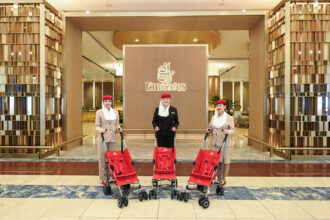 Three female Emirates staff stand behind three red strollers