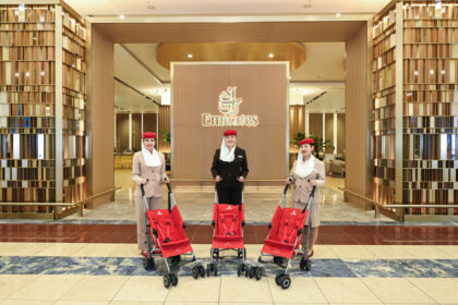 Three female Emirates staff stand behind three red strollers