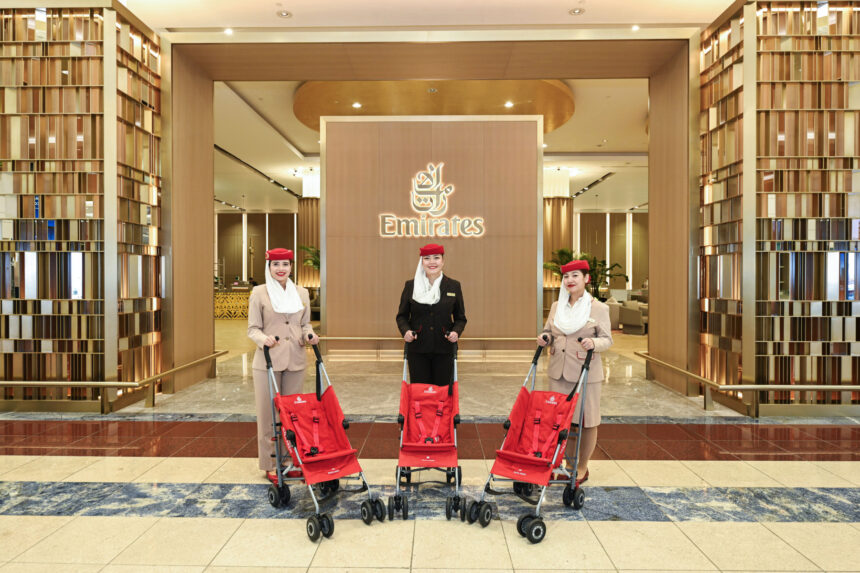 Three female Emirates staff stand behind three red strollers