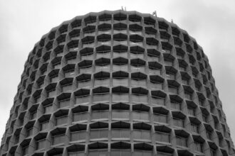 The Civil Aviation Authority UK's Head Office in London, taken from below looking up. The building occupies the whole photo, except for a strip of cloudy sky across the top and in the top corners.