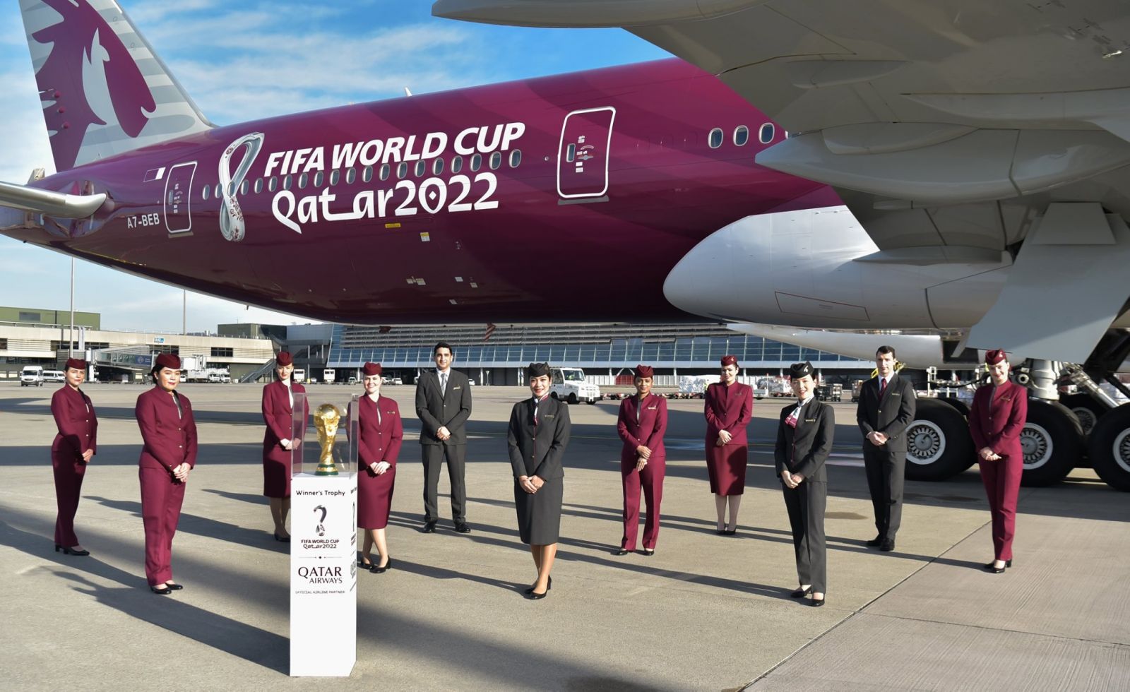FIFA World Cup Qatar 2022 aircraft with trophy and air hostesses stood in front of the plane on the tarmac.