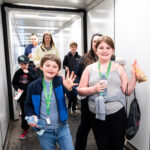 Children waving at the camera as they board the plane to experience a replication of aircraft procedures.