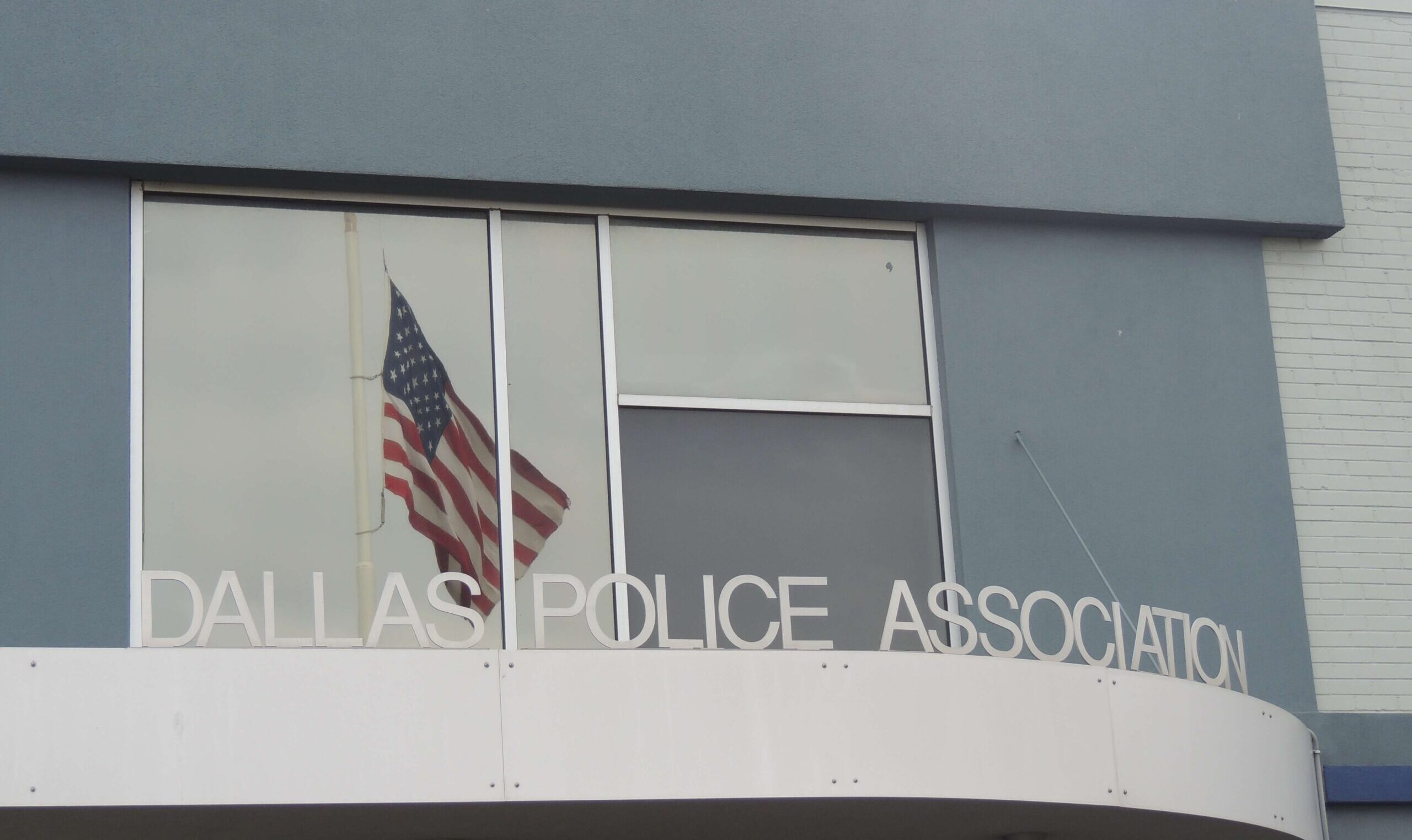 The Dallas Police Association building. An American flag shown in the reflection of a window.
