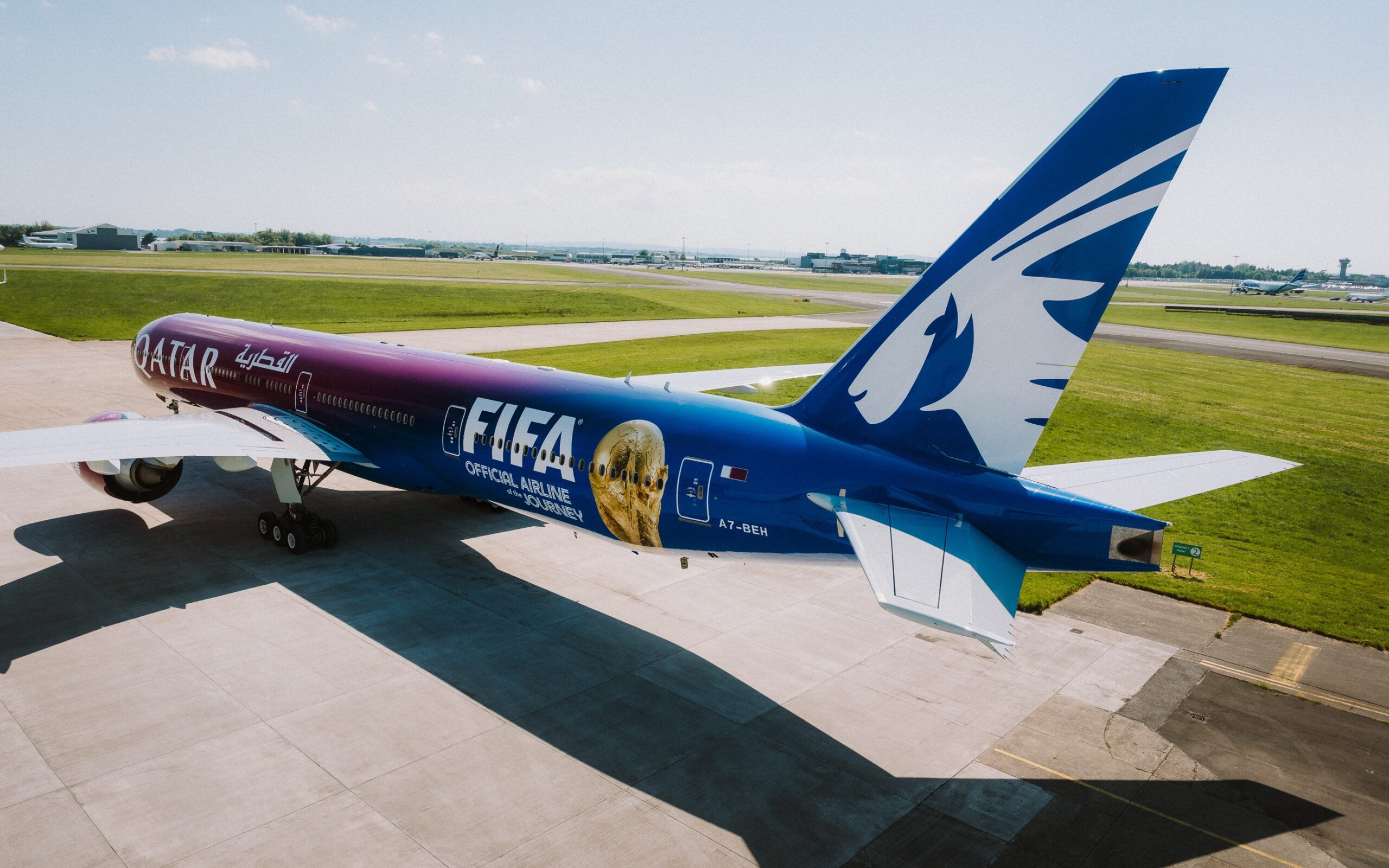 The aircraft in full showing the design and gradient colour from purple to blue on the tail with the Qatar and FIFA logos.