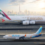 Emirates and flydubai aircraft on the runway with Dubai skyline in the background.