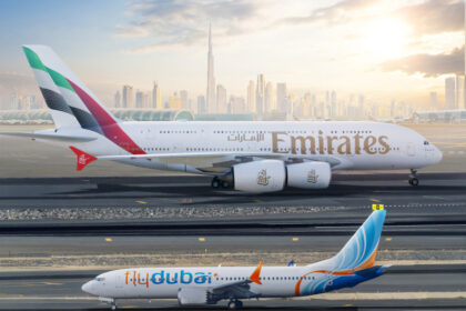 Emirates and flydubai aircraft on the runway with Dubai skyline in the background.