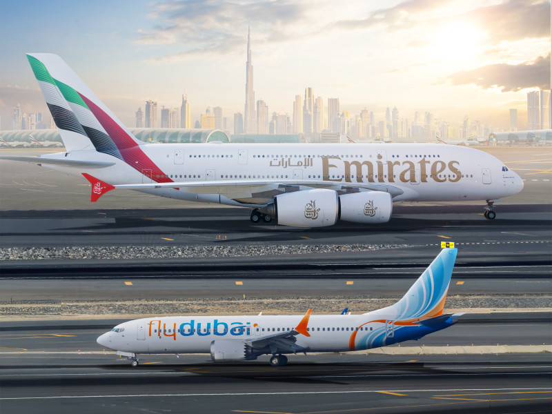 Emirates and flydubai aircraft on the runway with Dubai skyline in the background.