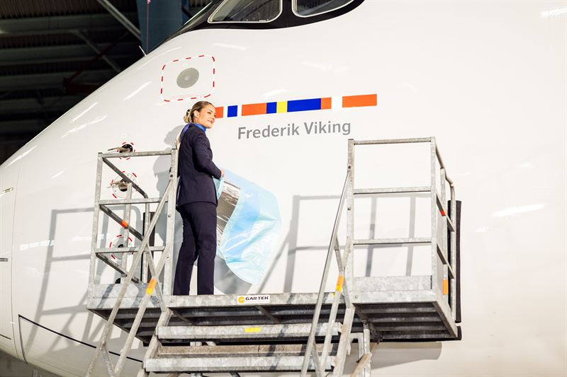 A lady representing SAS stands on top of some stairs at the cockpit of the aircraft. Above her head is the aircrafts new name- Frederik Viking