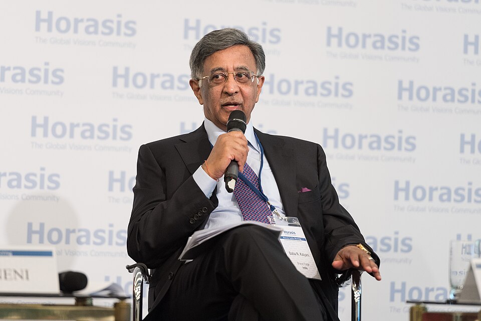 Portrait of Baba N. Kalyani, Chairman of Bharat Forge, seated at a conference table in formal attire during a business meeting.