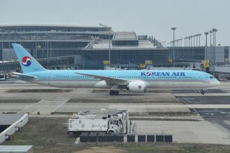 A Korean Air Boeing 787-10 in the airline’s distinctive light blue livery taxis past the terminal at Incheon International Airport, as the carrier moves toward its planned merger with Asiana Airlines in late 2026.