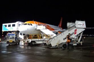 An easyJet Airbus A319 aircraft undergoes ground handling operations at night. The low-cost carrier plans to accelerate the retirement of its ageing A319 fleet as part of a wider strategy to modernise operations with newer, more fuel-efficient Airbus aircraft.