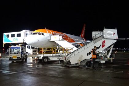 An easyJet Airbus A319 aircraft undergoes ground handling operations at night. The low-cost carrier plans to accelerate the retirement of its ageing A319 fleet as part of a wider strategy to modernise operations with newer, more fuel-efficient Airbus aircraft.