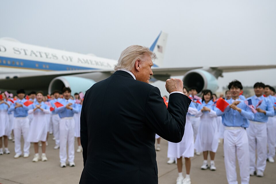 President Donald Trump raises his fist on the tarmac after arriving in China aboard Air Force One, greeted by rows of schoolchildren waving Chinese and American flags during an official welcome ceremony. 